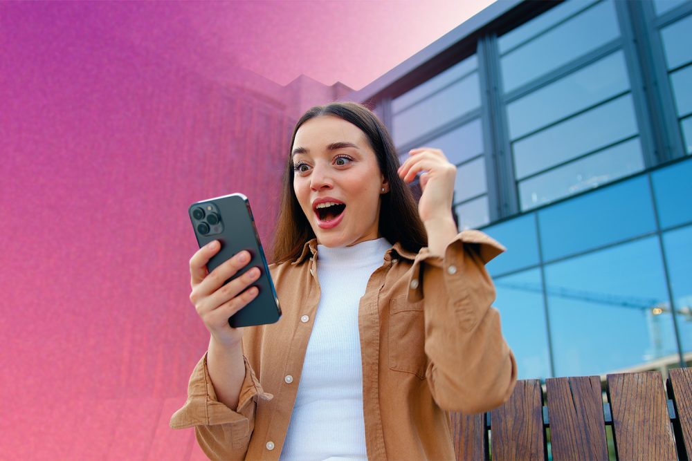 kobieta z telefonem patrząca z zaskoczoną miną